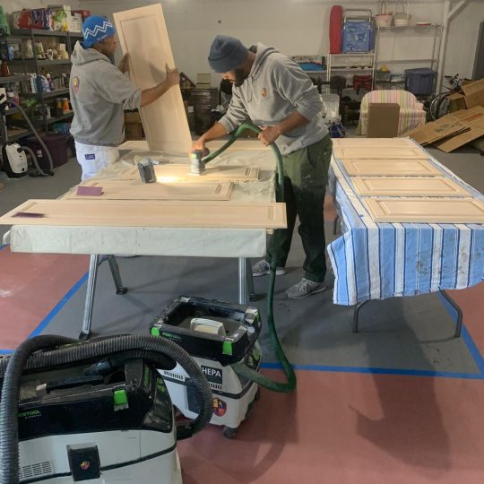 Sanding cabinet doors before applying first coat of primer.